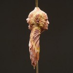 Laser Gold rod pierces a stone head fabricated by Barry X Ball